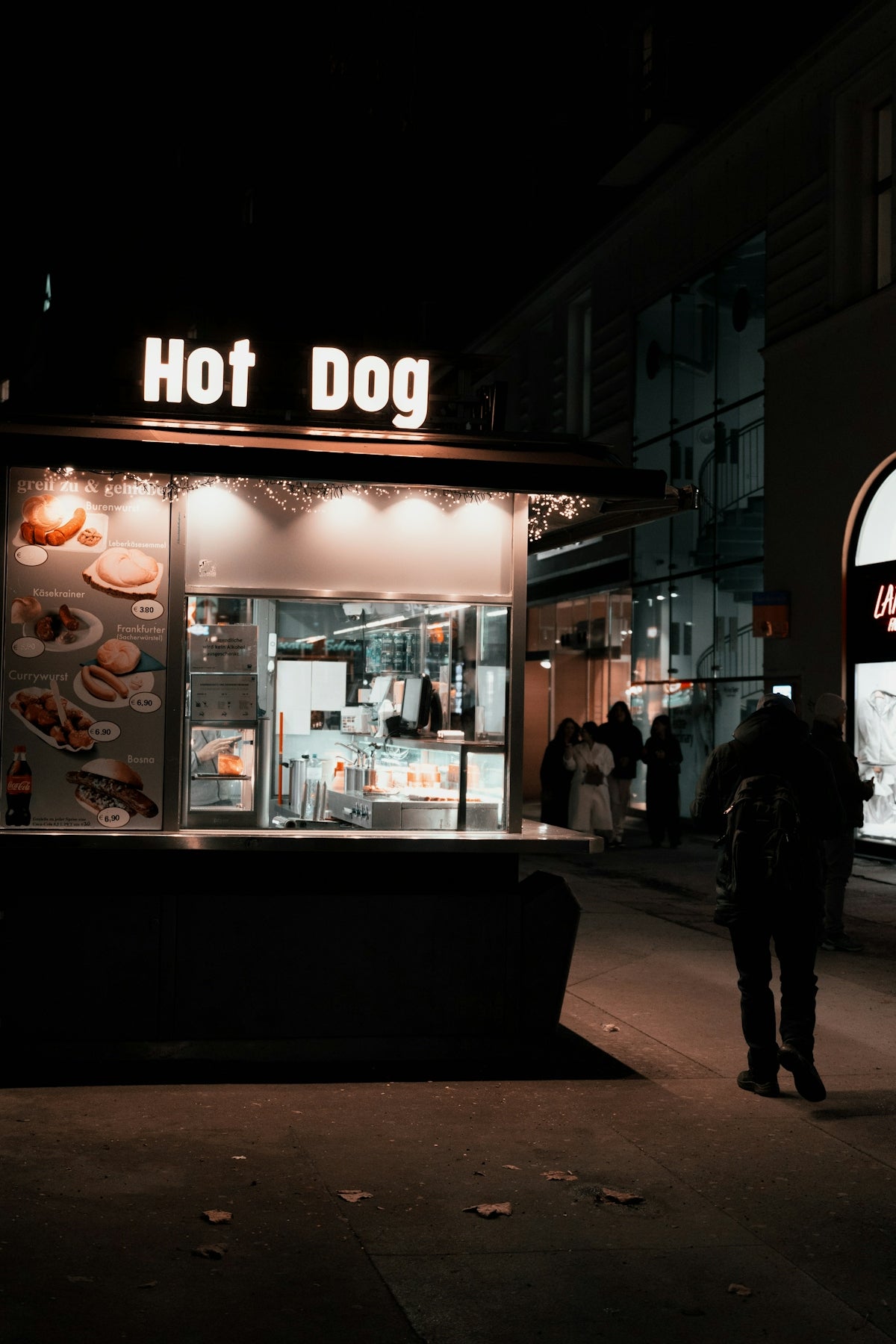 A hot dog stand on a city street at night